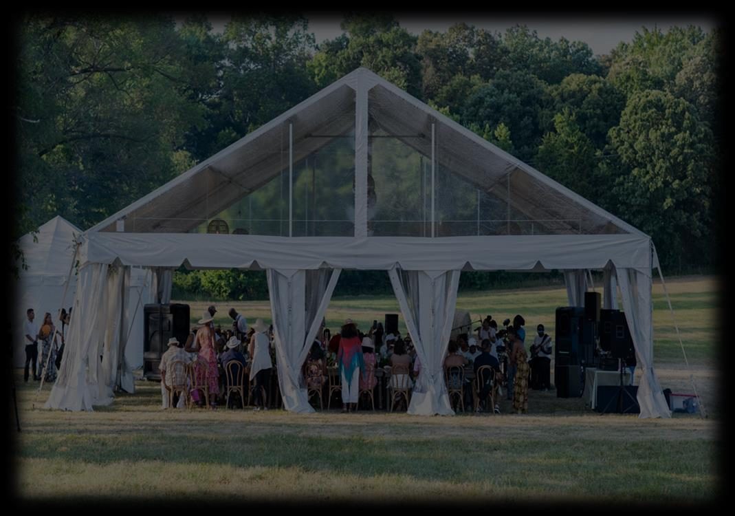 Community dinner under an open-sided tent in an open field at golden hour