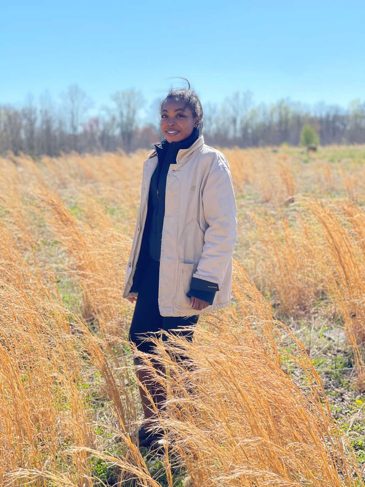 Kathy Mason standing in a field of golden winter grasses on the farm