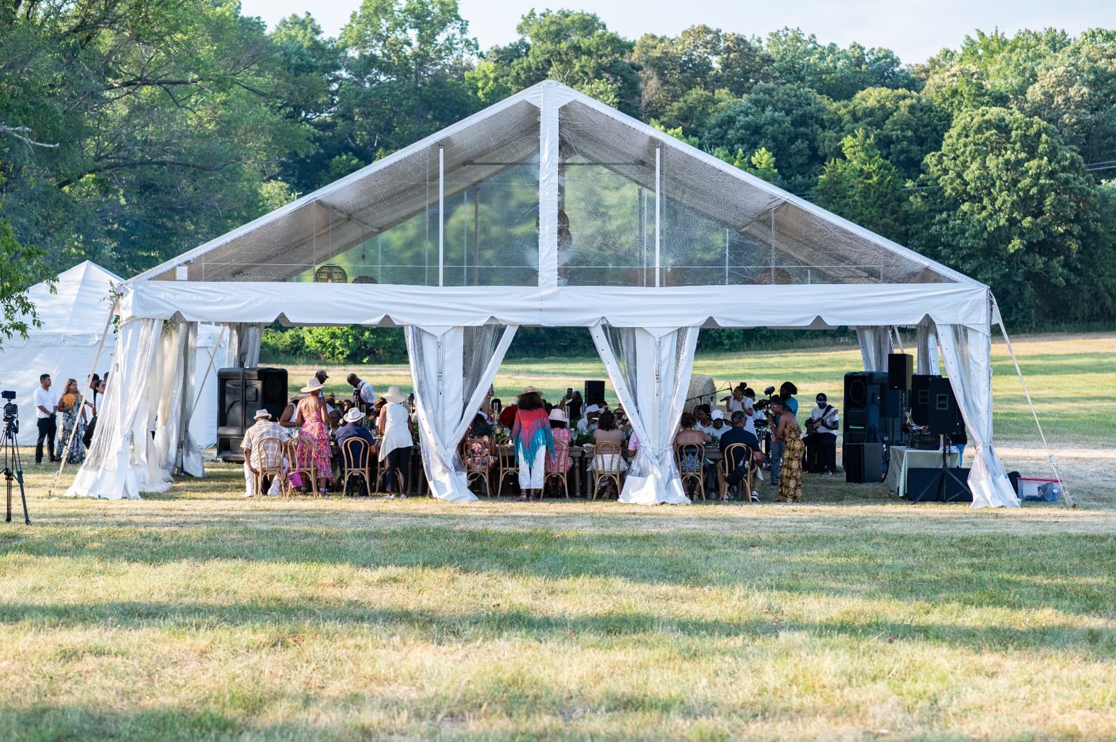 Guests seated at a long table under a clear-top tent during the first community event held on the farm